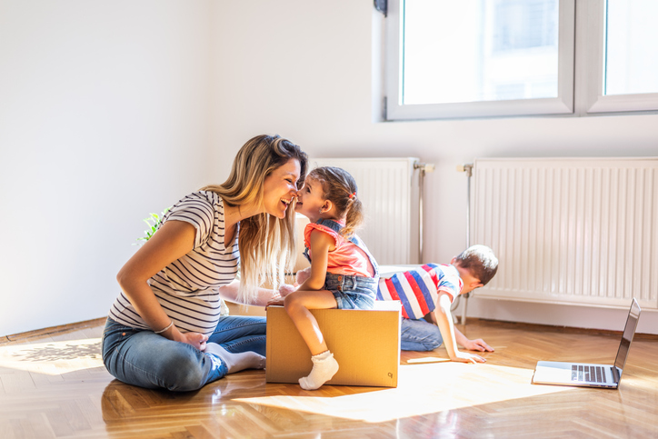 Pregnant mom with 2 toddlers with boxes in new apartment